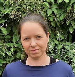 Kopf von Jenny Scholl vor einer Hecke